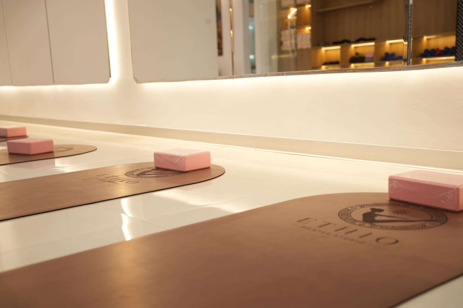Embossed leather Ethio Pilates mats laid out with soft pink blocks under warm light